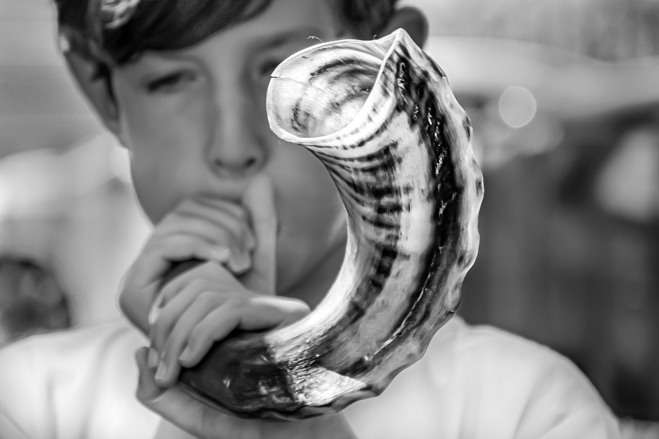 A young boy blows a shofar on Yom Kippur